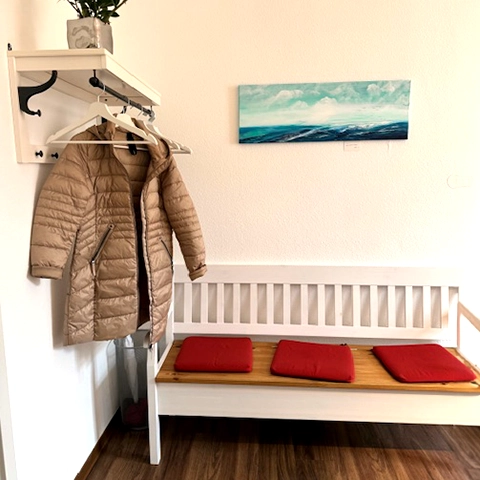 Praxiswartezimmer mit weißer Bank und Garderobe