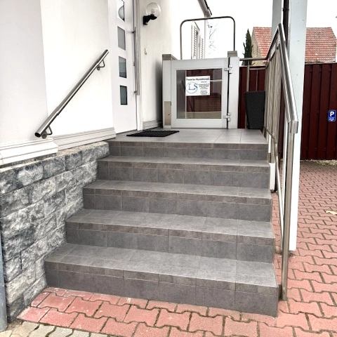 Praxiseingang mit Treppenaufstieg und behindertengerechten Aufzug ausgestattet