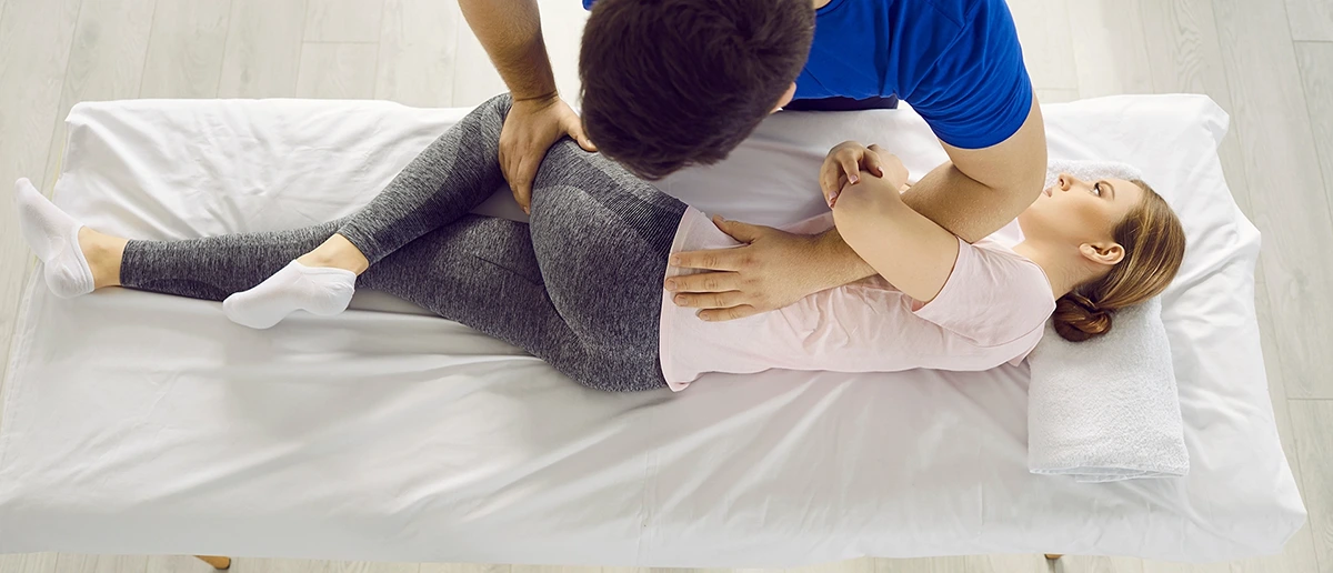 Männlicher Physiotherapeut hilft dem Klienten, Muskelschmerzen zu lindern und sich nach einer Verletzung oder einem Trauma zu erholen.